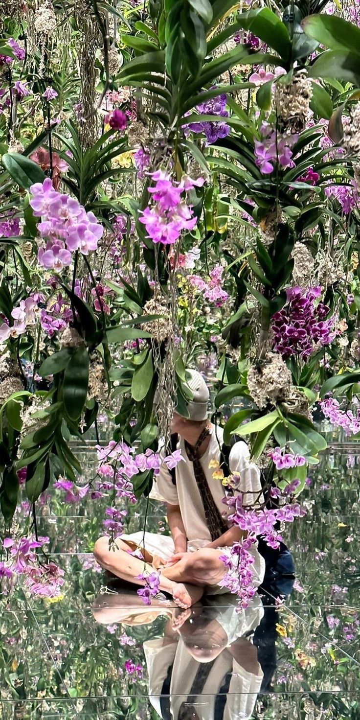 a man sitting in the middle of a field with purple flowers on his head and body