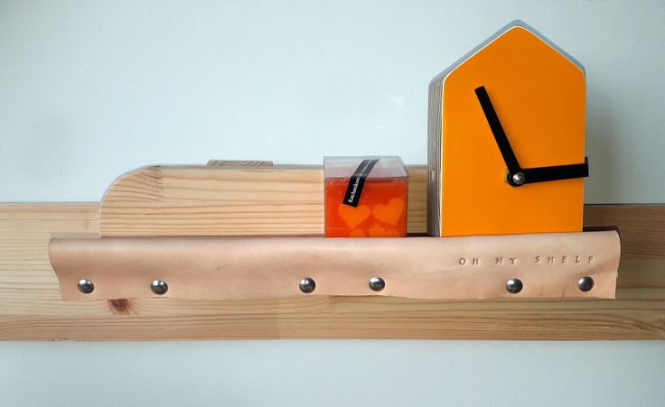 an orange clock sitting on top of a wooden shelf