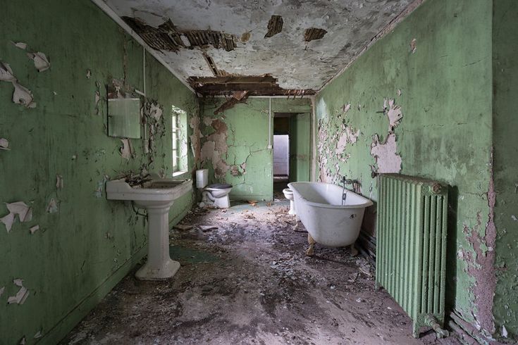 an old run down bathroom with peeling paint on the walls and floor, including a claw foot bathtub