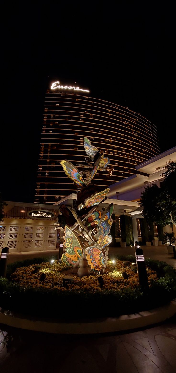 a large butterfly sculpture in front of a building at night