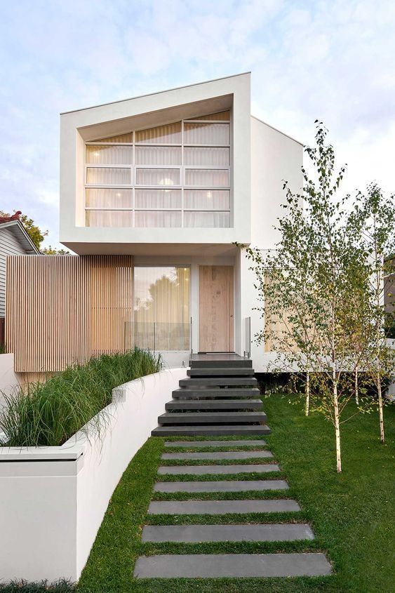 this modern house has steps leading up to the front door and side entrance, along with grass