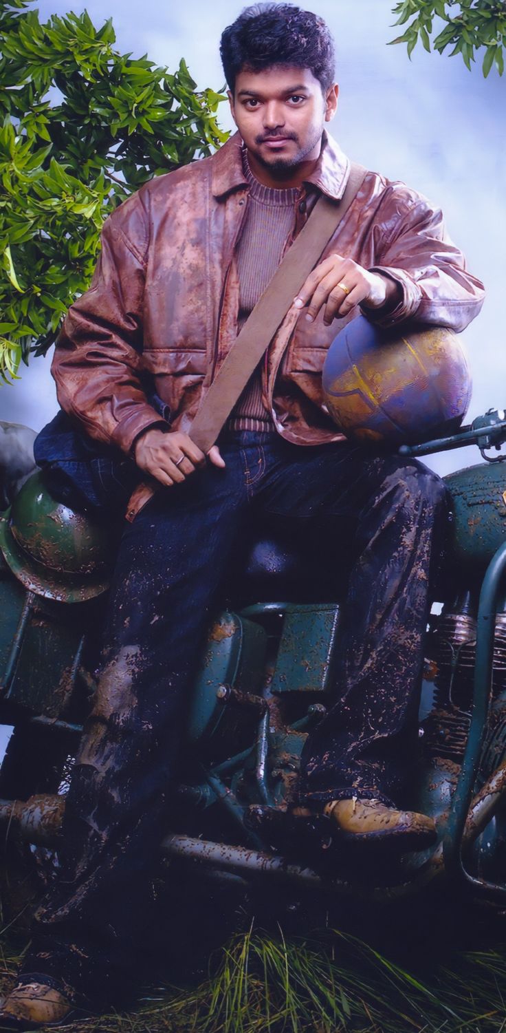 a man sitting on the back of a green tractor with a brown leather jacket over his shoulder