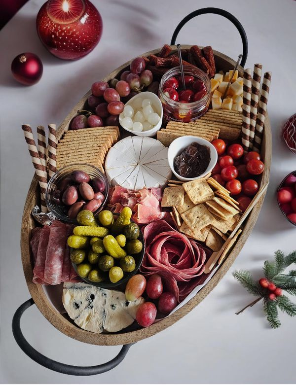 a platter filled with meats, cheeses and other food items next to christmas decorations