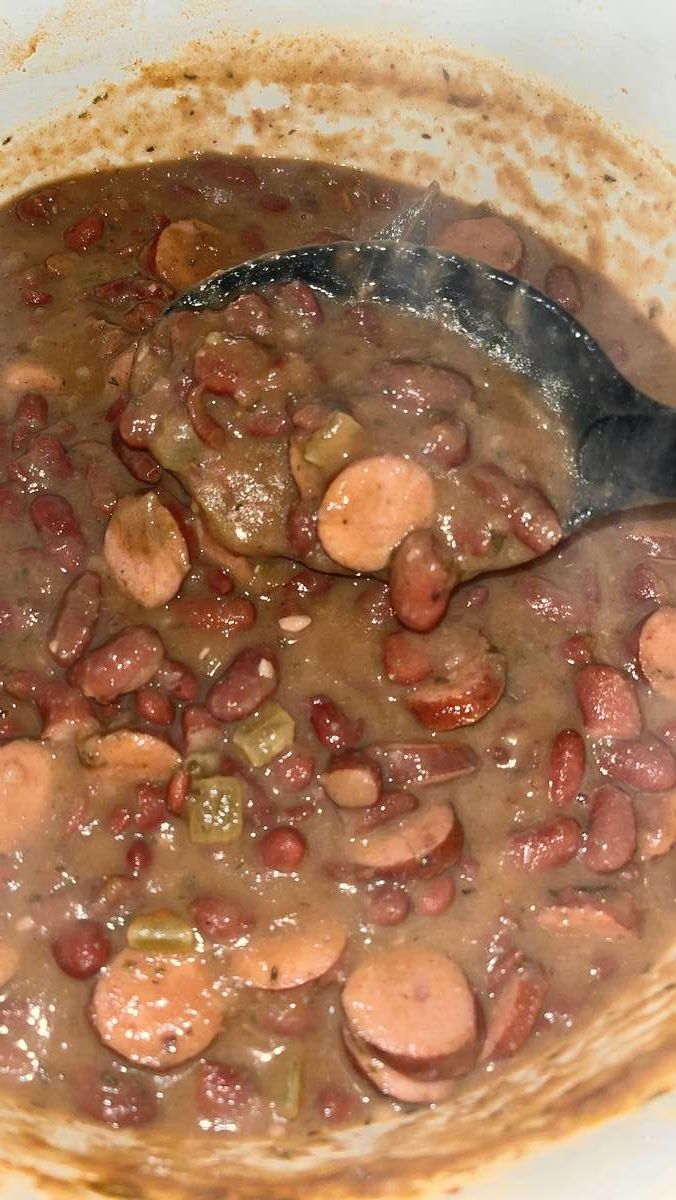 a pot filled with beans and sausages on top of a stove