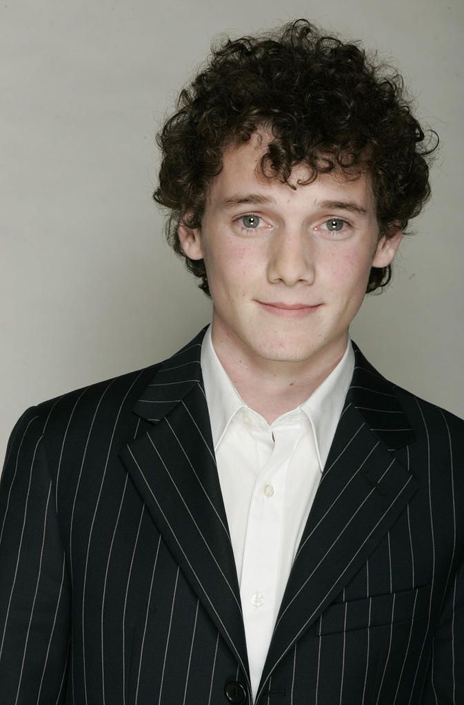 a young man with curly hair wearing a suit