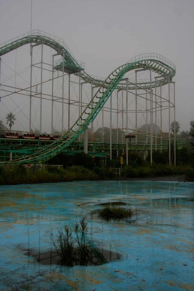 a roller coaster in an amusement park on a foggy day with blue water around it