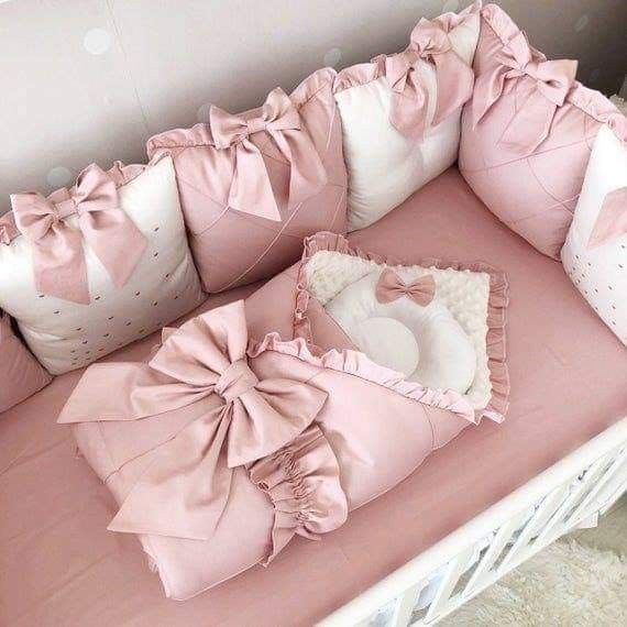 a baby crib with pink bedding and pillows