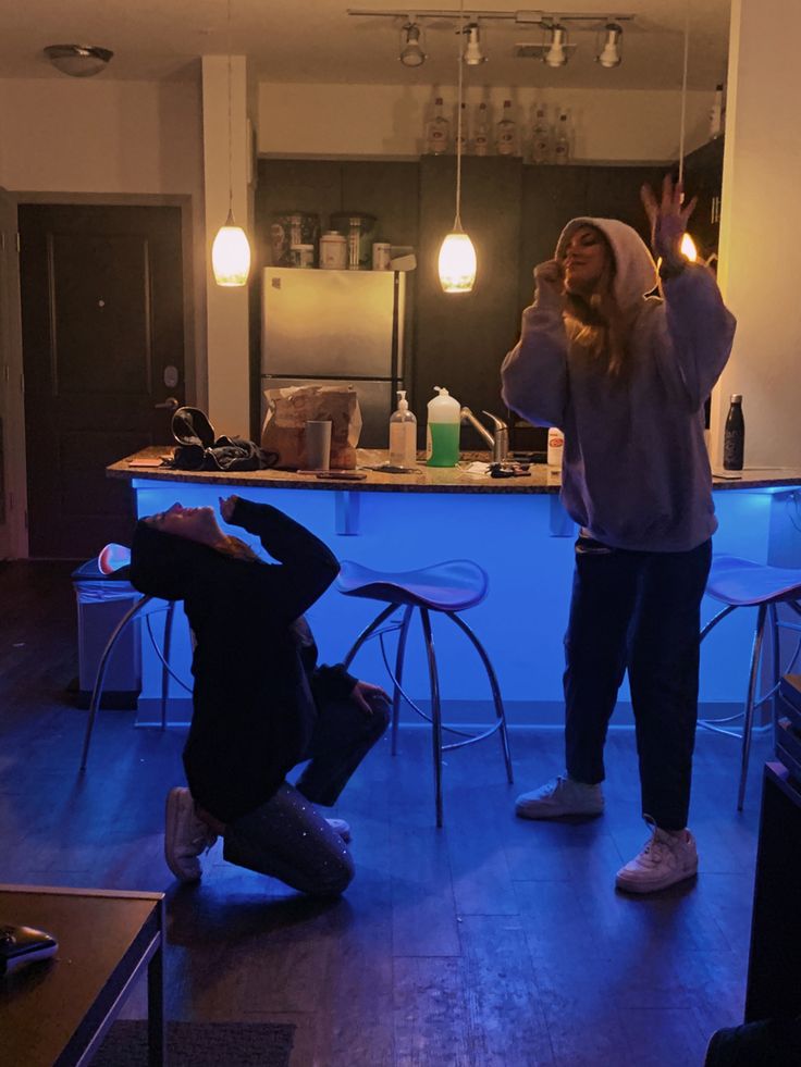 two people standing in a room with lights on and one person holding up their hands