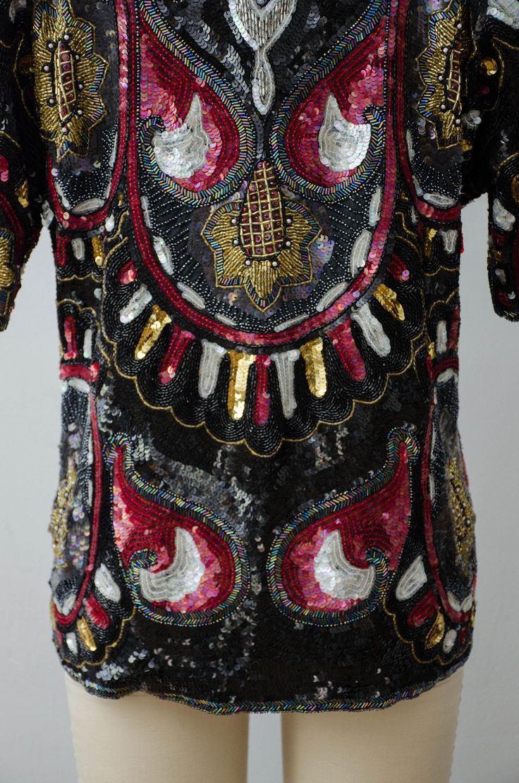 A pure silk shirt with black sequins and beading made in India by Jean for Joseph Le Bon. Very intricate beading completely covers the entire shirt in black, red, and iridescent sequins with beading in silver, iridescent black, red, gold, and iridescent white￼. Gold sunflower details are found on the front, back and sleeves. A pull-on style, it has no closures and is meant to fit loosely. With all of the beading, the weight of the blouse is close to 3 pounds. ☛ m e a s u r e m e n t s ☚ Bust: 39 Elegant Embellished Multicolor Blouse, Silk Party Tops With Sequins, Glamorous Silk Top With Sequins, Glamorous Sequined Silk Top, Glamorous Silk Sequined Top, Bohemian Sequin Tops For Night Out, Glamorous Hand Embellished Tops For Party, Glamorous Hand Embellished Party Tops, Embellished Multicolor Blouse For Festivals