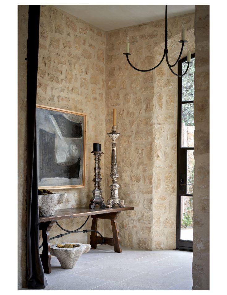 a table with two candles on it in front of a painting and chandelier