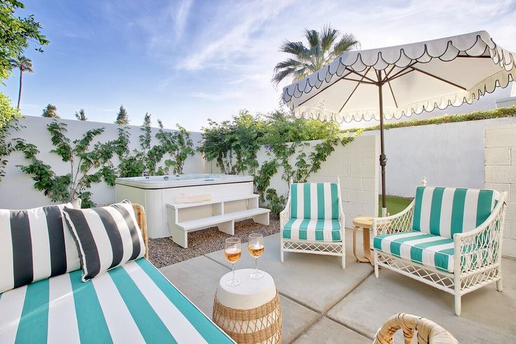 an outdoor living area with striped furniture and umbrella