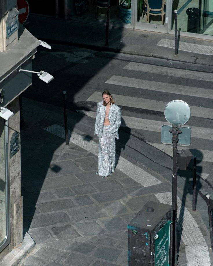 a woman walking across a street next to a cross walk