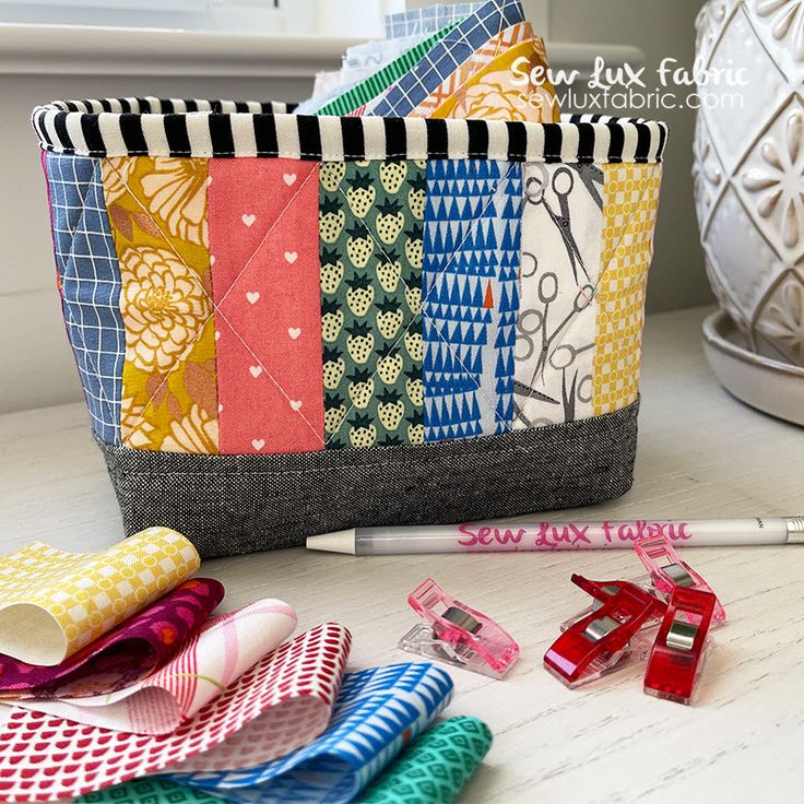 a pencil case filled with lots of different colored fabric items next to a white vase