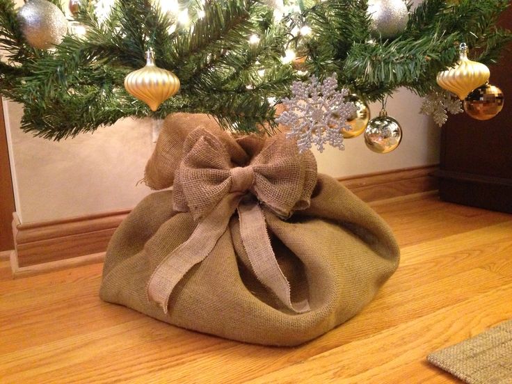 a christmas tree in a burlock bag on the floor with ornaments around it