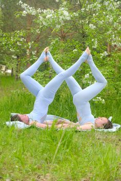 two women doing yoga in the grass with their hands behind their heads and legs crossed