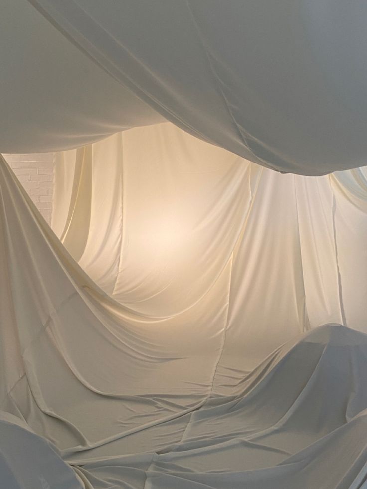 a room with white drapes covering the walls and floor, as if it were an art installation