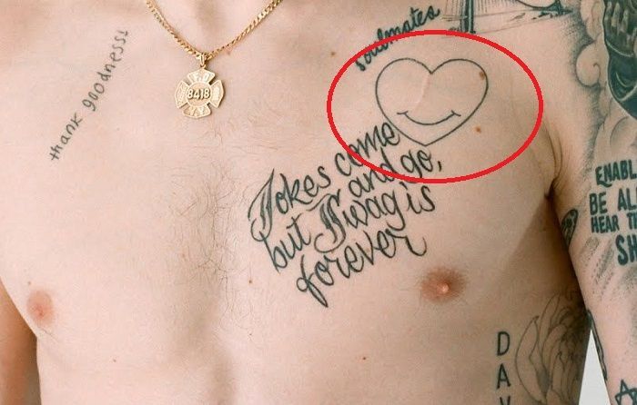 a man with tattoos on his chest has a red circle in front of the chest