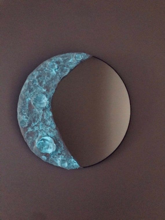 a circular mirror sitting on top of a table next to a moon shaped wall hanging