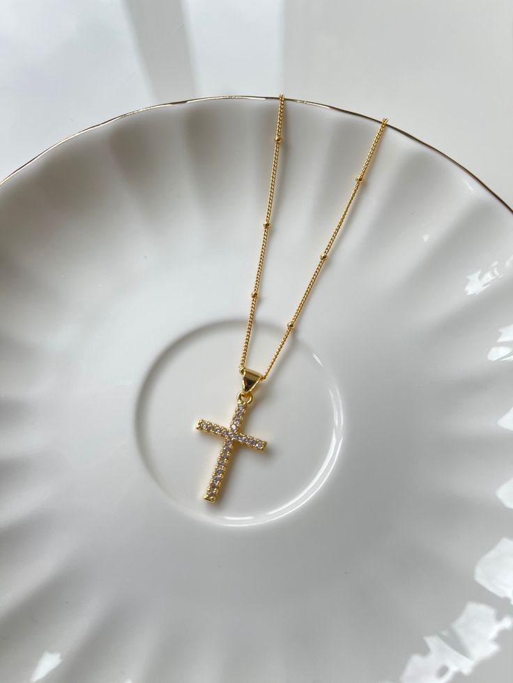 A meaningful symbol, the Cross Pendant Necklace is lined with gems and shines to bring new life to a classic. The cross brings maximum shine with a delicate touch meant to be worn everyday, layered or on its own. Suspended on our dainty beaded golden chain. Details: The length of the Cross Pendant Necklace is 16 inches with an additional 2.5-inch extender chain to easily adjust the length, providing a total adjustable length of up to 18.5 inches. The pendant measures 15 mm in diameter. SHIPPING Gold Plated Cross Necklace With Delicate Chain, Dainty Crucifix Cross Necklace With Delicate Chain, Gold-plated Cross Necklace With Adjustable Chain, Gold Plated Cross Necklace With Adjustable Chain, Dainty Gold Crucifix Cross Necklace, Gold Crucifix Cross Necklace With Delicate Chain, Golden Chain, Cross Pendant Necklace, The Cross