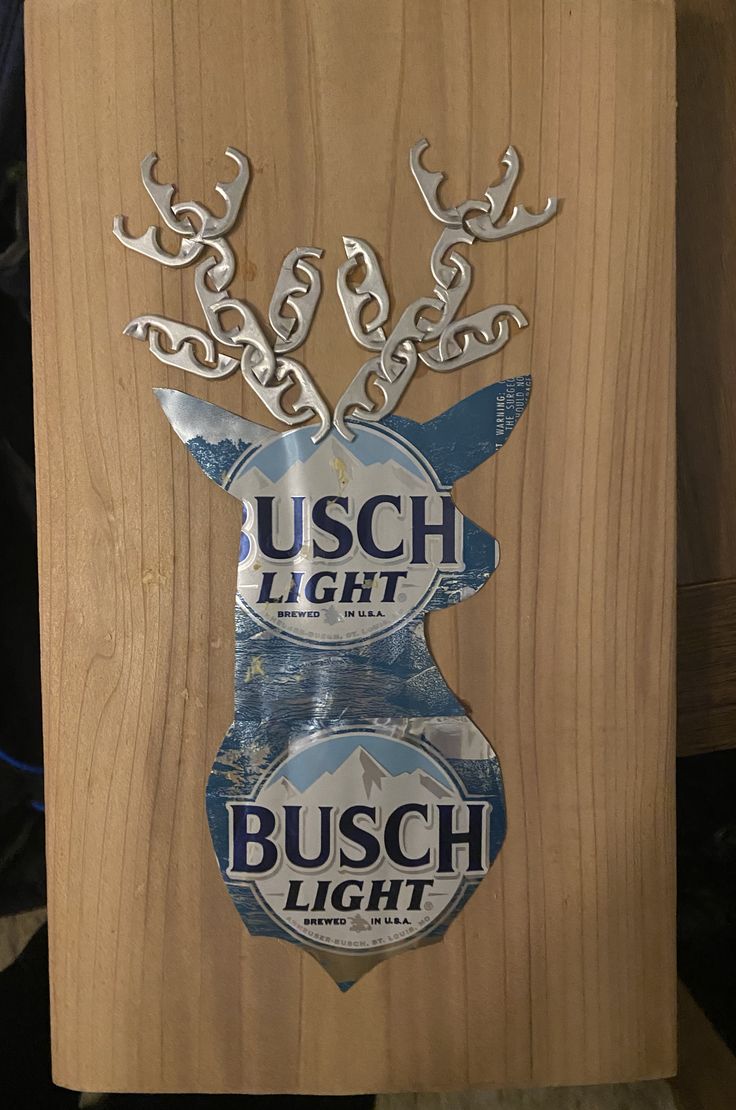 a wooden sign with metal deer head and busch light stickers on it's side