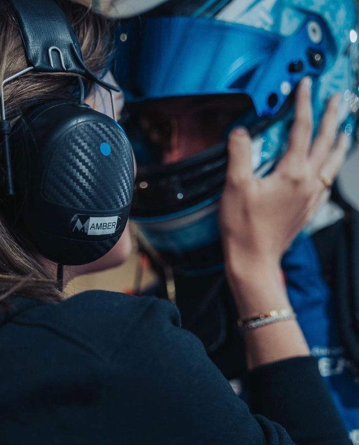 a woman wearing headphones and a helmet is looking at something on the wall behind her