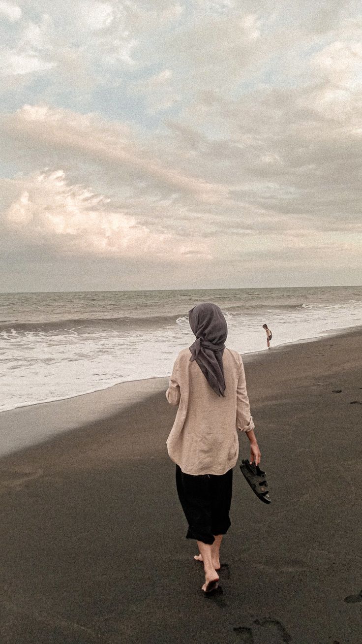 a woman walking along the beach with her dog