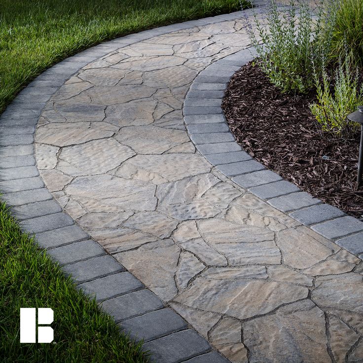 a stone path in the middle of some grass