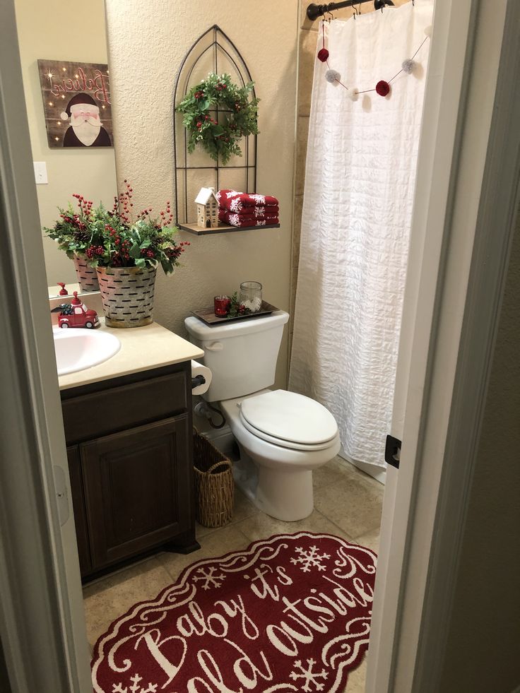 a bathroom decorated for christmas with red and white decorations on the shower curtain, toilet seat cover and rug