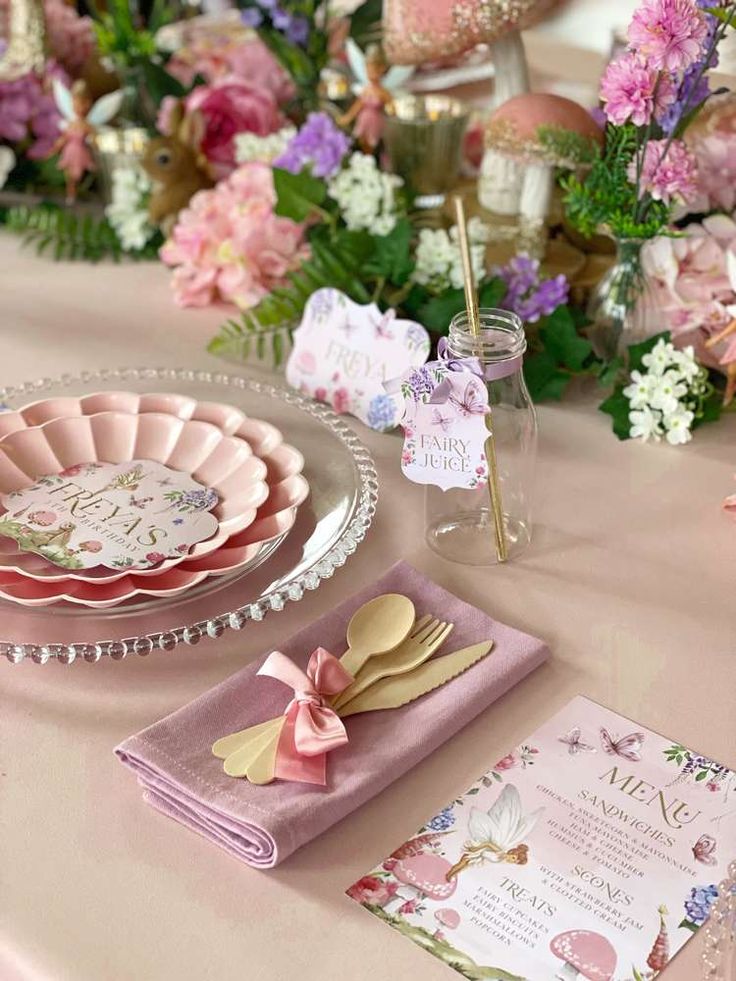 a table topped with plates and napkins covered in pink flowers