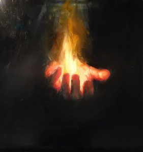 a person holding out their hand in front of a fire on a black background with light coming from behind it