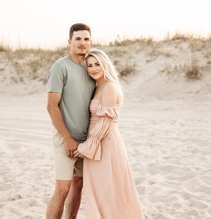 a man and woman standing on top of a sandy beach next to eachother