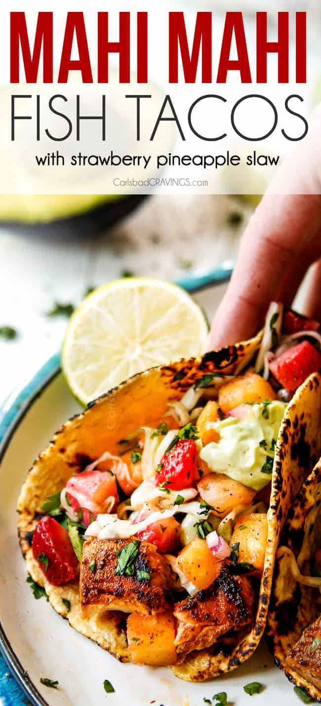 a plate with fish tacos on it and a hand holding the tortilla