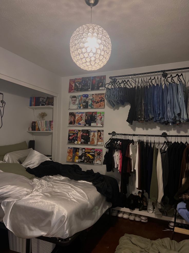 an unmade bed sitting in a bedroom next to a closet with clothes hanging on the wall