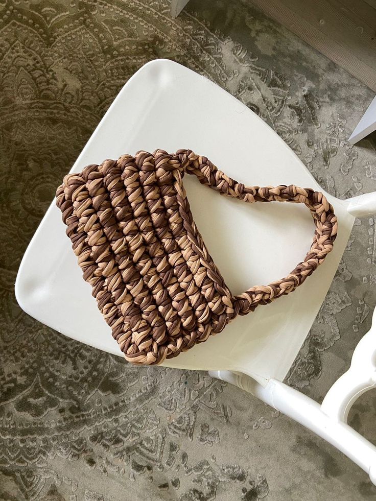 a woven purse sitting on top of a white chair