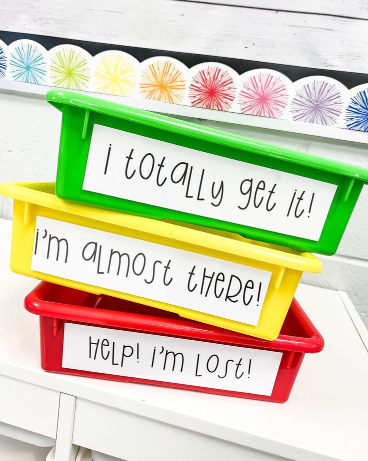 three plastic containers with words on them sitting on top of a white table next to colorful paper plates