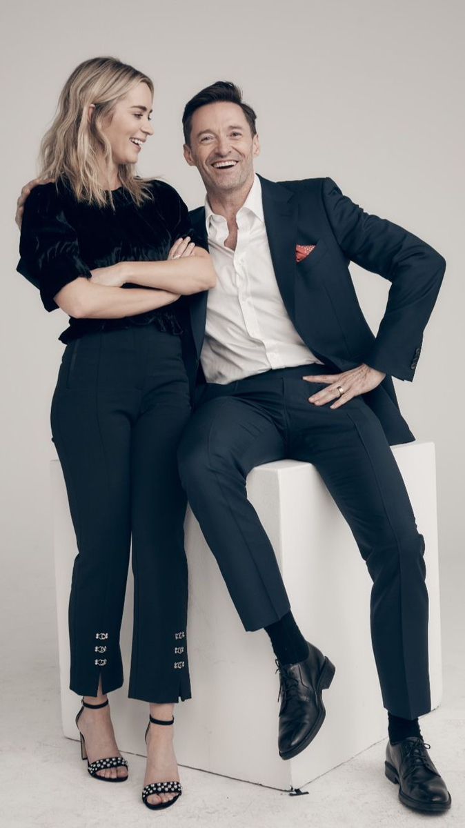 a man and woman sitting on top of a white block posing for the camera with their arms around each other