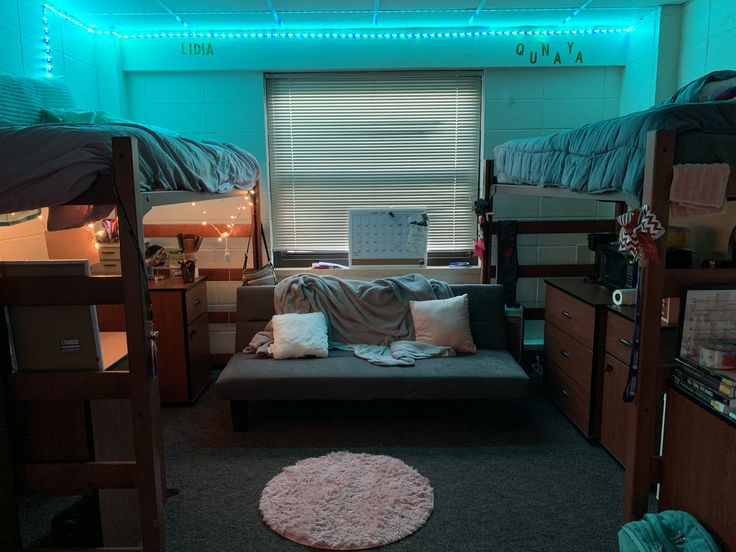 a dorm room with bunk beds, desks and lights on the ceiling is lit up