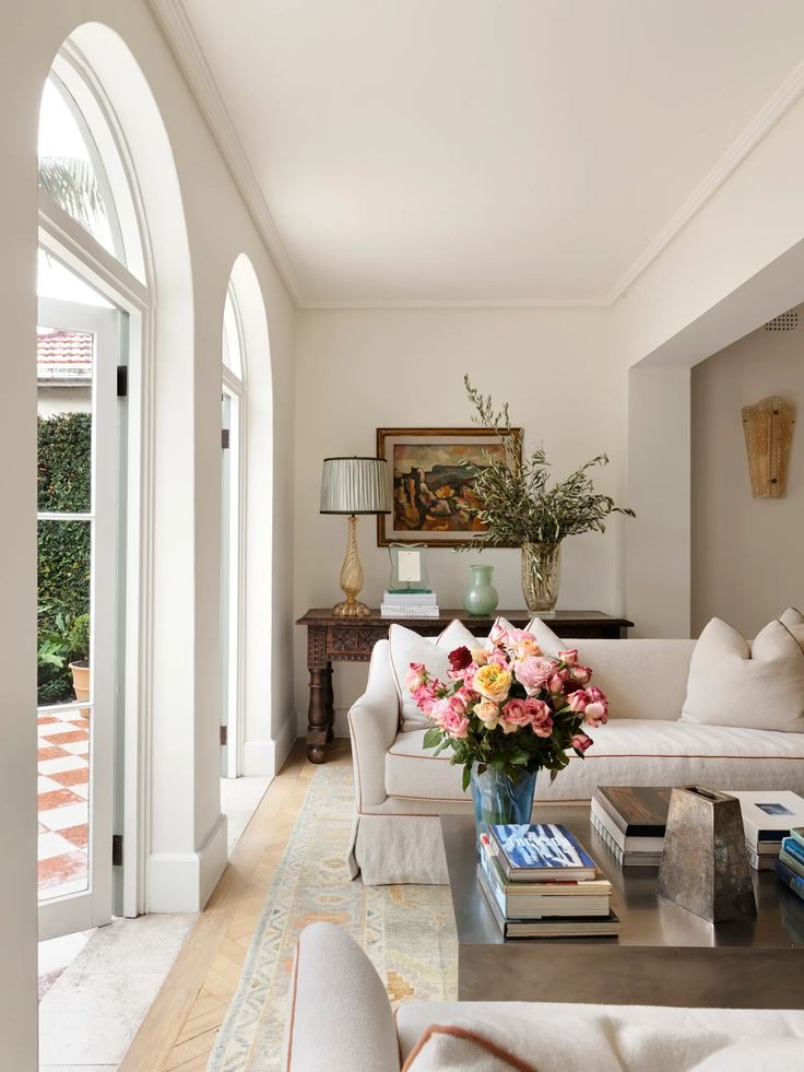 a living room filled with lots of furniture and flowers on top of a coffee table