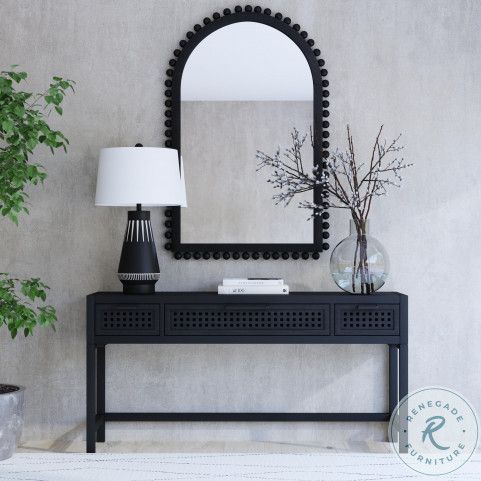 a black console table with a lamp and mirror on it next to a potted plant