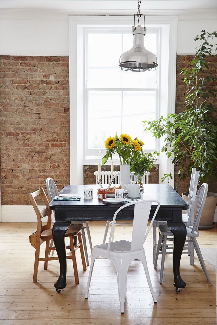 a dining room table and chairs with sunflowers on the window sill in the background