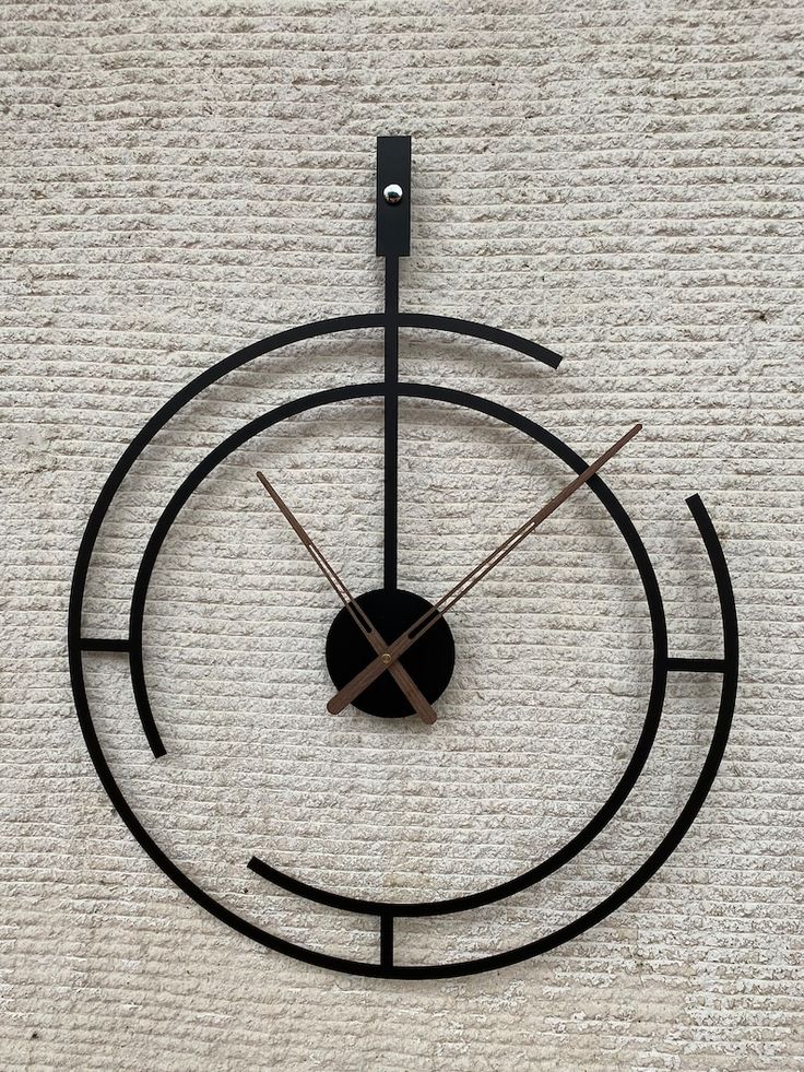 a clock that is sitting on the floor in front of a carpeted area with a white wall behind it