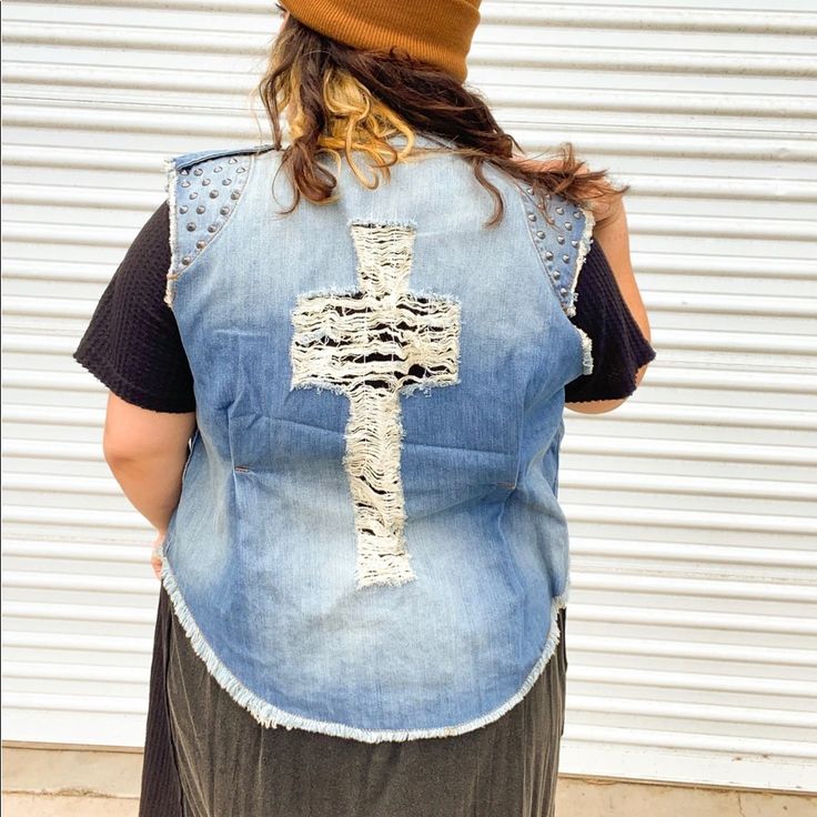 a woman wearing a denim vest with a cross on it