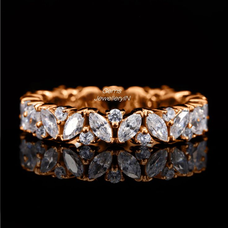 a yellow gold ring with five pear shaped diamonds on the side, set against a black background