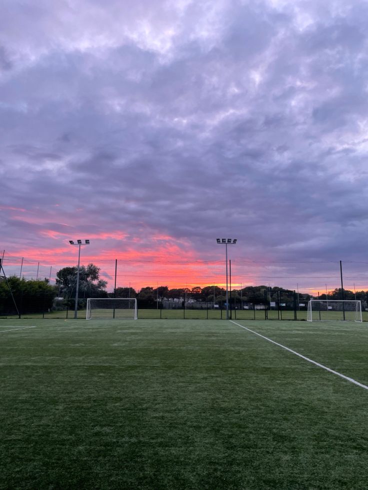 a soccer field with the sun setting in the background