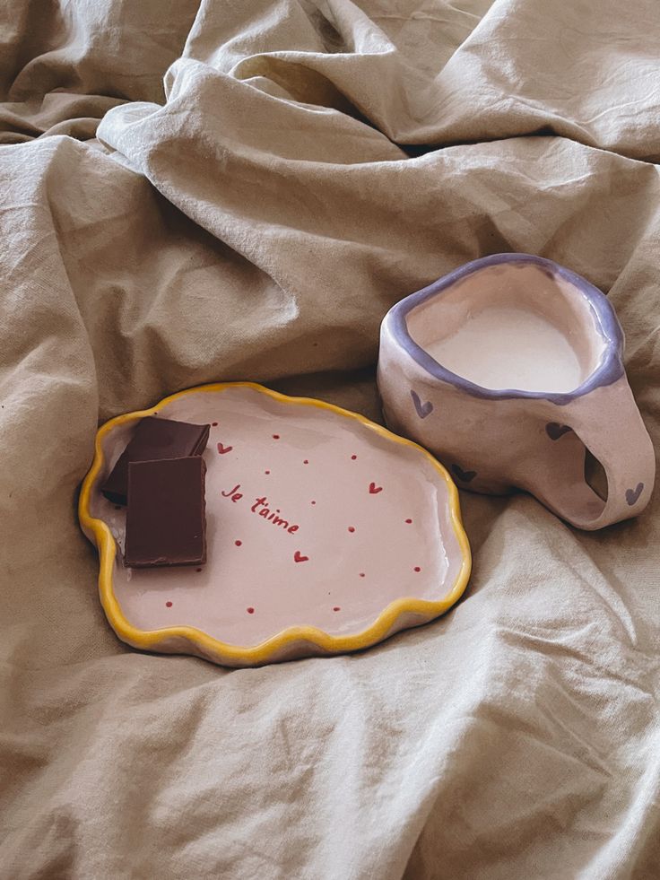 a plate with a piece of chocolate next to it on a bed