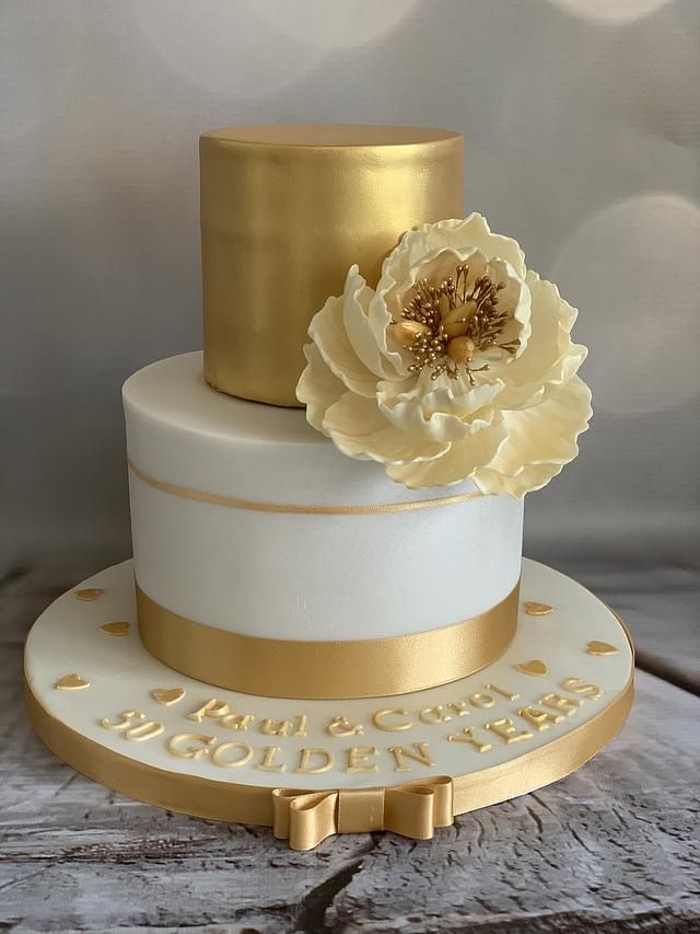 a white and gold wedding cake sitting on top of a wooden table