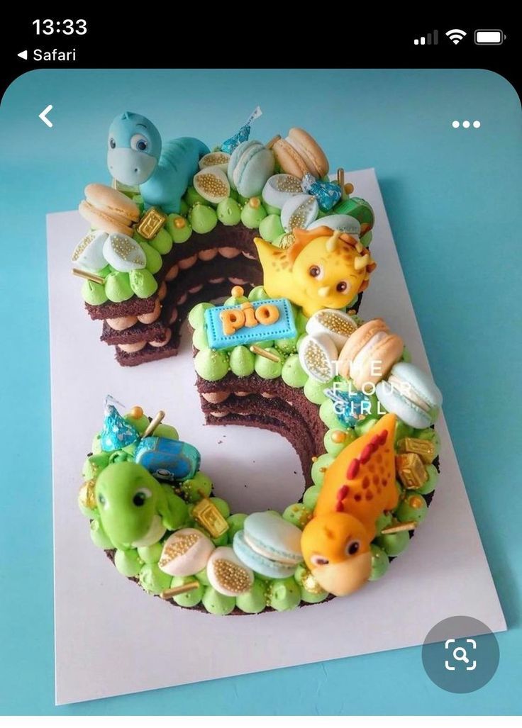 a birthday cake shaped like the number five with animals and decorations on it, sitting on top of a piece of paper