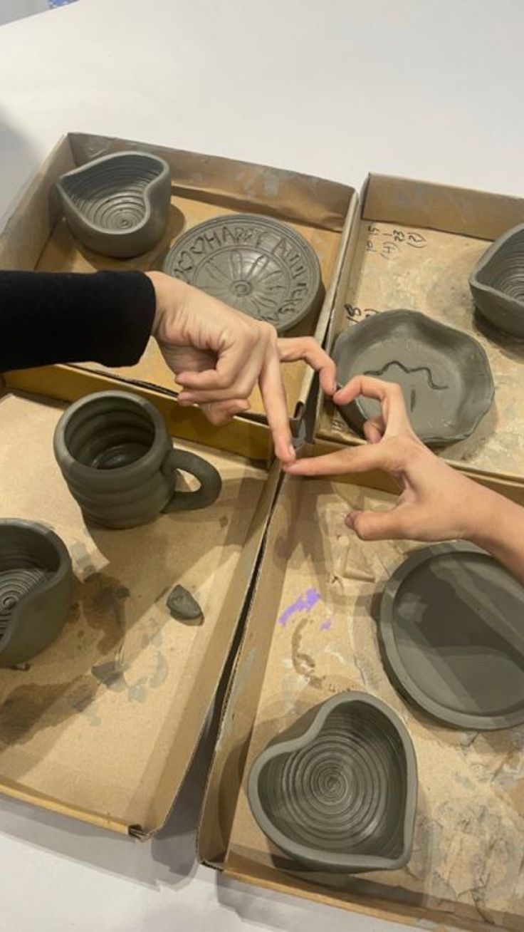 two people are making clay pots in a box