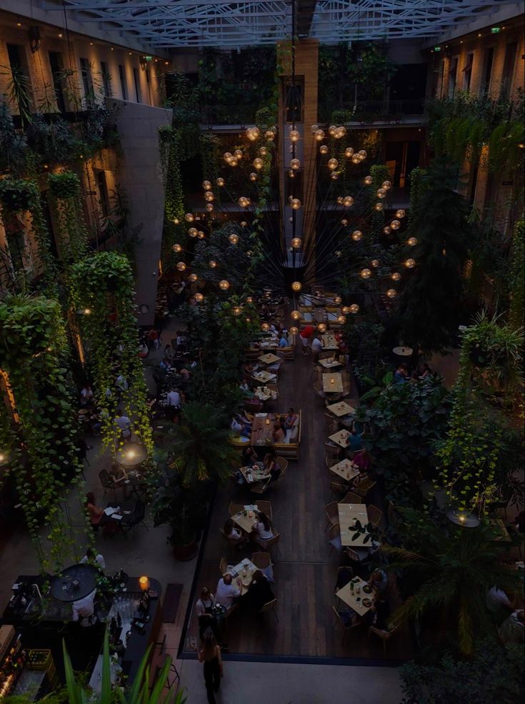 an overhead view of a restaurant with lots of tables and plants on the walls, along with lights hanging from the ceiling