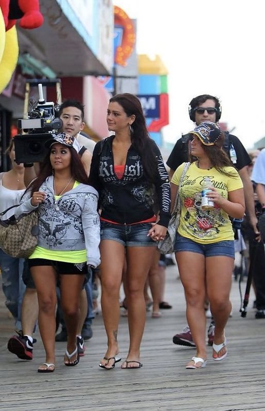 three girls walking down the boardwalk with cameras on their heads and one girl holding a camera